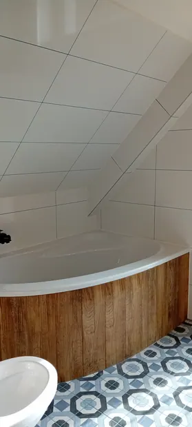 Vana s dřevěným obkladem pod šikmým stropem.