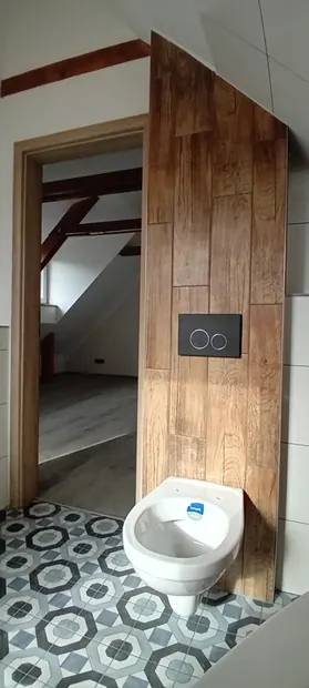 Závěsné WC u stěny s dřevěným dekorem.