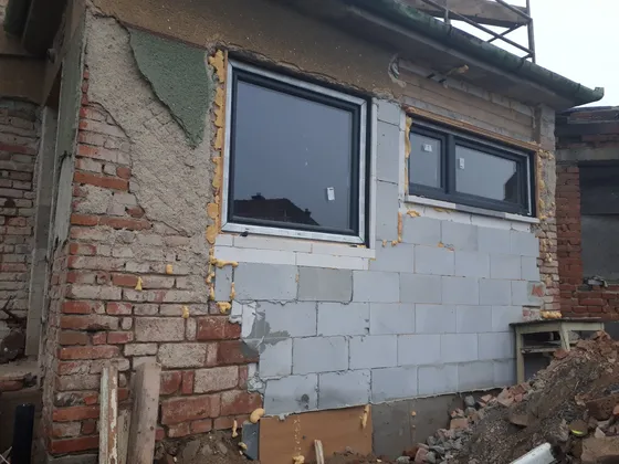 Pohled zvenku na osazené okno a navazující stavební práce.