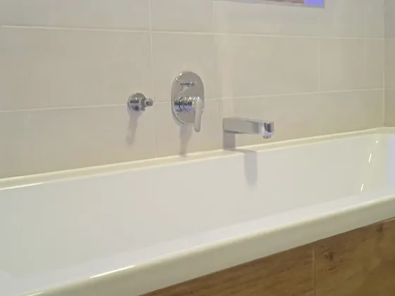Dokončená vana, podomítkové baterie a dřevodekorový obklad.
