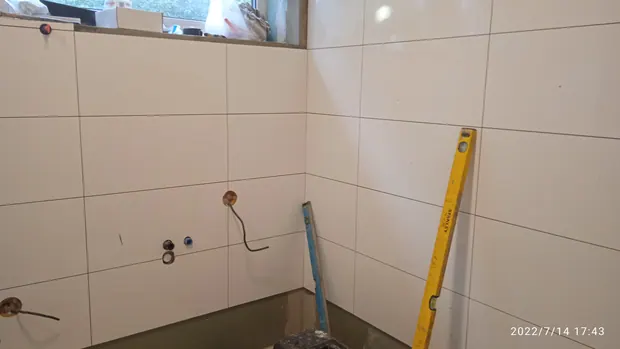 Stěna koupelny pod oknem při přípravě vývodů pro umyvadla.