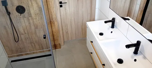 Pohled na sprchu s dřevěným dekorem a dvojumyvadlo.