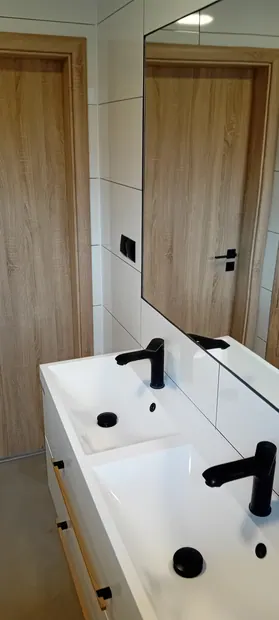 Detail dvou umyvadel s černými bateriemi.