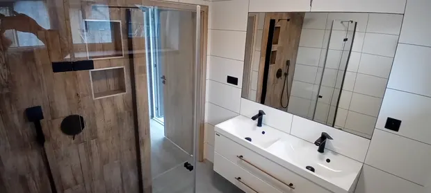 Dokončená přízemní koupelna se sprchou a dvojicí umyvadel.