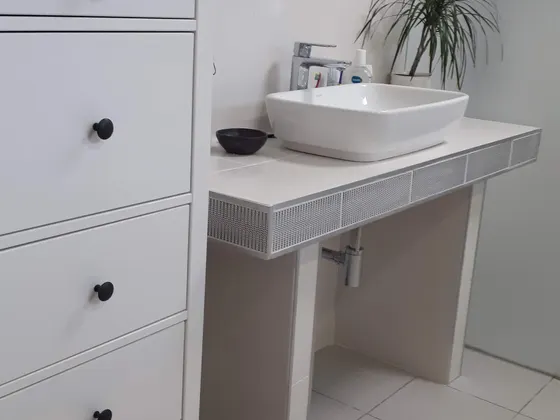 Hotová umyvadlová zóna s deskou, povrchovým umyvadlem a zrcadlem.