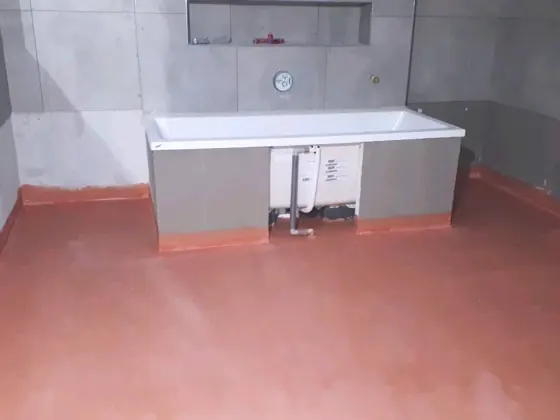 Hydroizolace podlahy a příprava vany v jedné z koupelen.