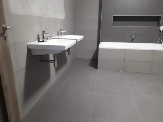 Dokončená koupelna s dvojumyvadlem, vanou a nikou.