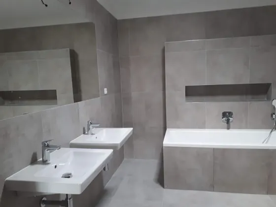Pohled na dokončenou koupelnu s vanou a čistým detailem obkladů.