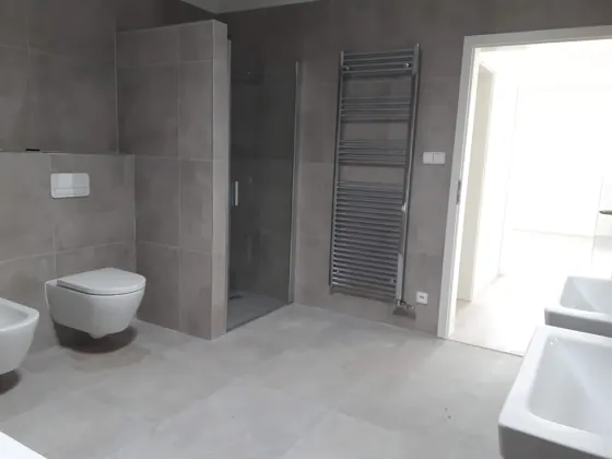 Dokončená koupelna se sprchou, WC, bidetem a topným žebříkem.