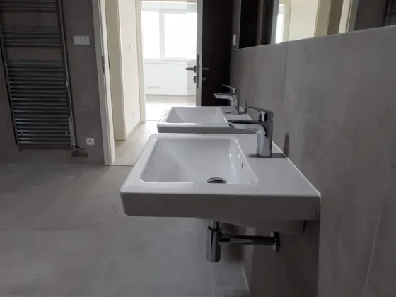 Detail hotové koupelny s dvojumyvadlem, velkoformátovou dlažbou a topným žebříkem.