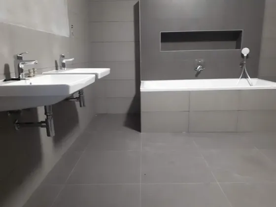 Další hotová koupelna s vanou, nikou a dvojicí umyvadel.