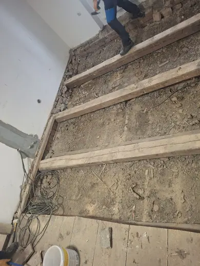 Odkrytá prkenná podlaha a původní trámová konstrukce v kuchyni farního domu.