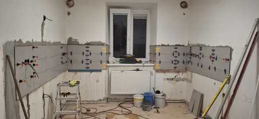 Pokládka obkladu na stěny před osazením kuchyňské linky.