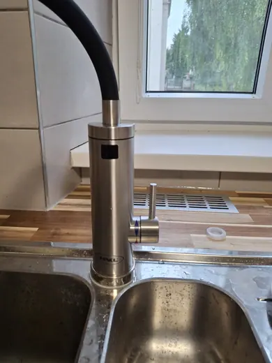 Detail dřezu, kuchyňské baterie a pracovní desky.