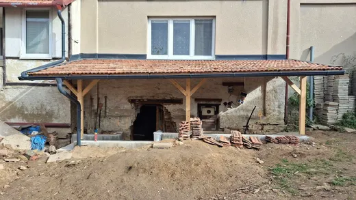 Celkový pohled na dřevěnou pergolu a zastřešený vstup do sklepa.
