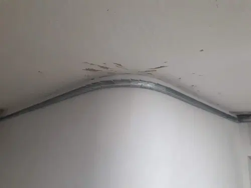 Detail kovových profilů při přípravě napojení podhledu na stěnu.