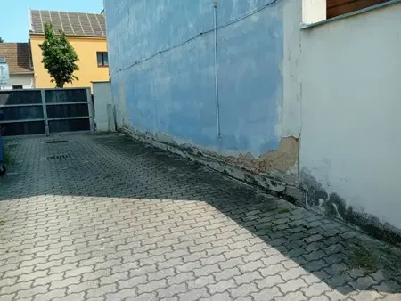 Před opravou: poškozený sokl a omítka modré boční stěny ve dvoře.