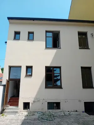 Dvorní fasáda domu před opravou poškozeného soklu.