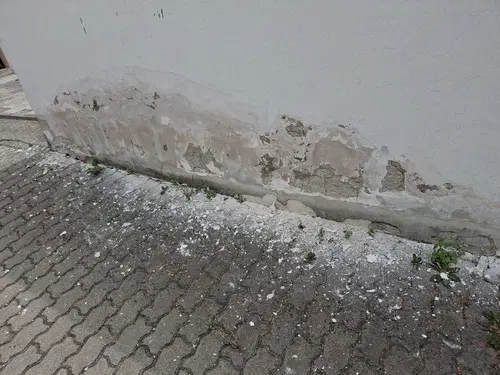 Porušená omítka na bílé stěně ve dvoře.