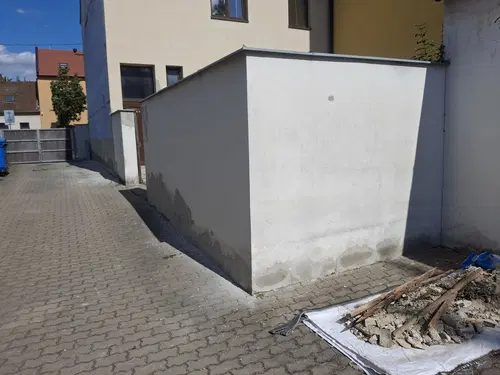 Bílá stěna ve dvoře po lokální opravě poškozené omítky.