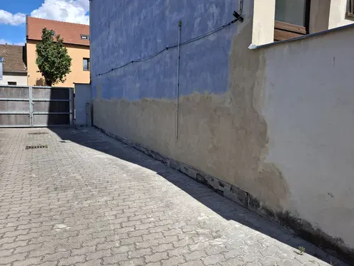Boční stěna po opravě soklu a navazující plochy před finálním nátěrem.