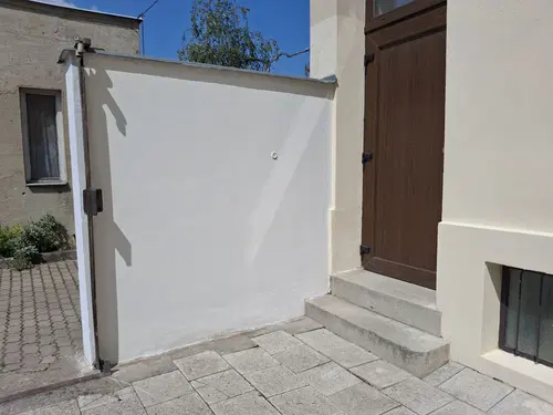 Dokončená bílá stěna u vstupu do dvora.