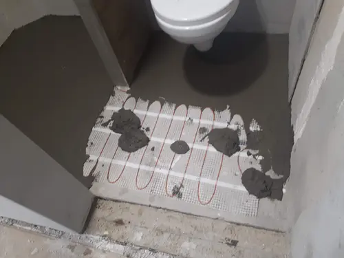 Elektrické podlahové topení v prostoru závěsného WC během pokládky.